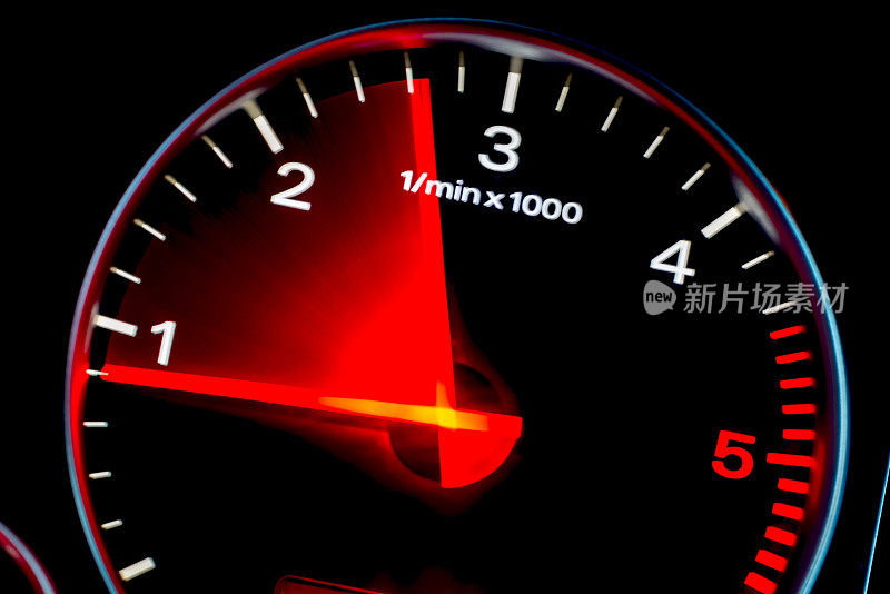 运动模糊的汽车仪表盘里程表与红色照明显示。汽车速度表。高速汽车测速仪和夜间运动模糊。
