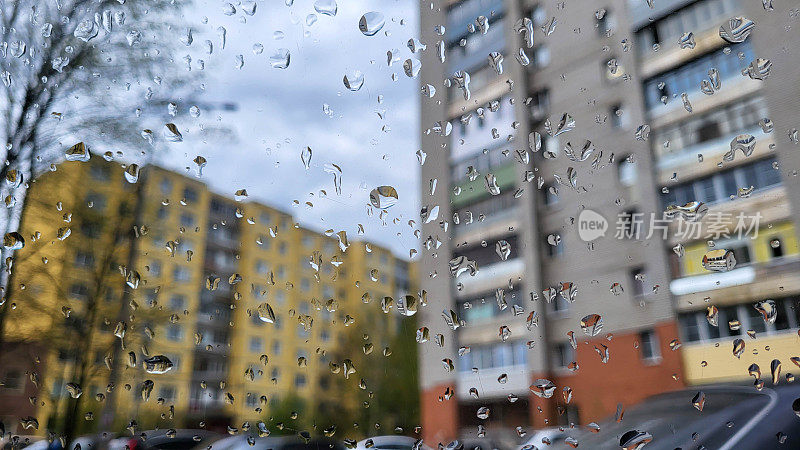 在一个阴天，雨滴落在院子里的车窗上。