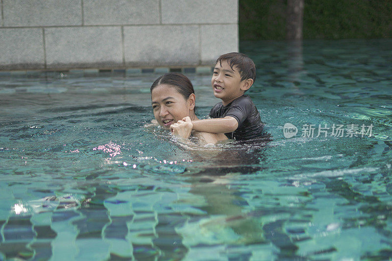 妈妈和男孩在游泳池里游泳