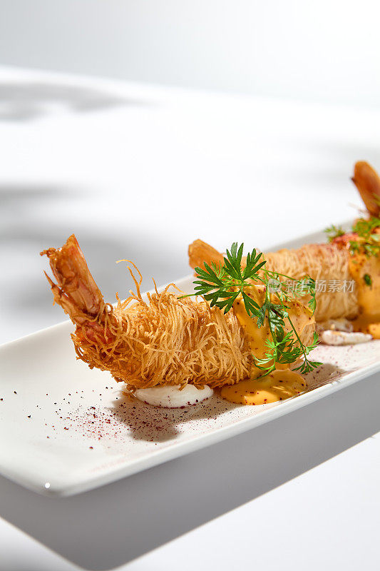传统的希腊开胃菜——用白色盘子包裹的虾。夏日的脆皮虾。虾开胃菜炸在kataifi面团。现代风格的脆皮对虾。