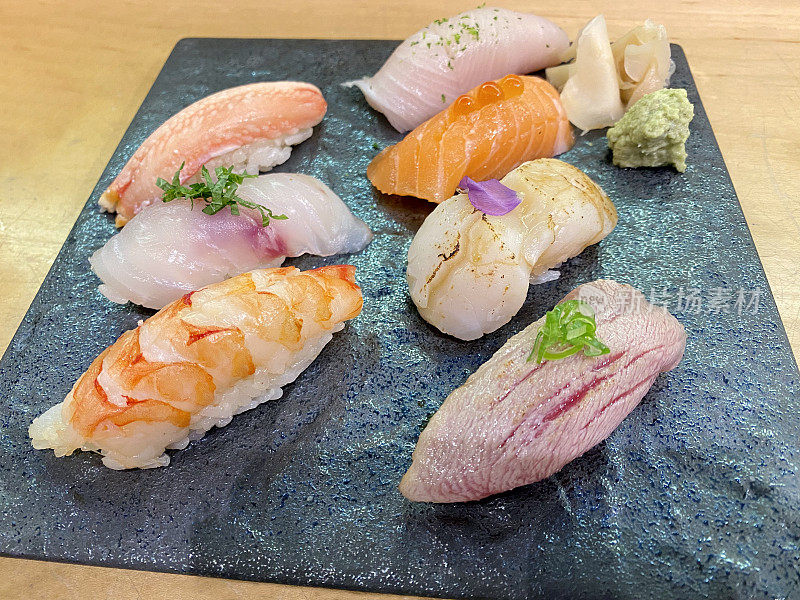 顶视图原汁原味寿司与山葵和gari在黑色石板石板板在木纹背景。