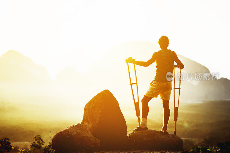 残疾人拄着拐杖站在群山的背景下