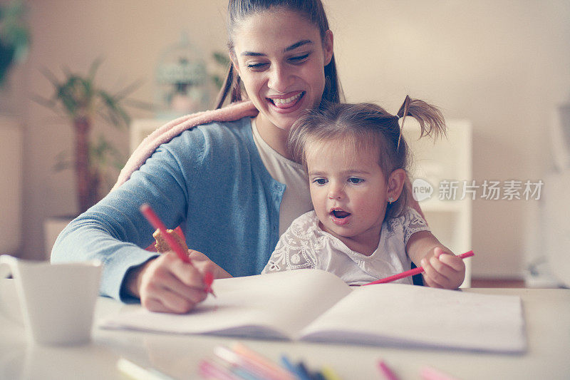 母亲和女儿在家里玩蜡笔。