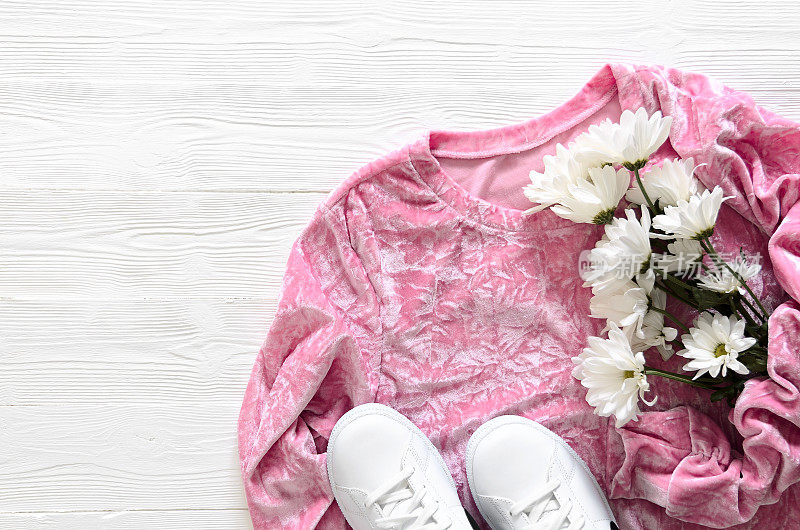 女士时装，鞋子(白色运动鞋，粉色天鹅绒毛衣)在木制背景与复制空间。时尚的概念。从上面看，平坦。春夏系列