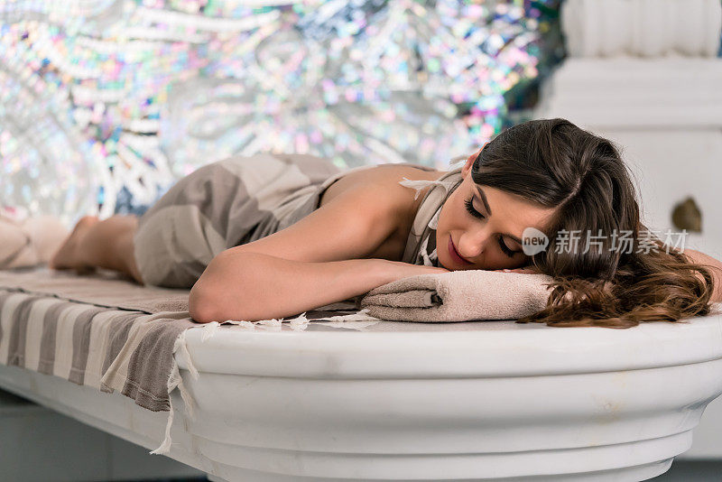 美丽的女人躺在滚烫的大理石桌上准备洗土耳其浴