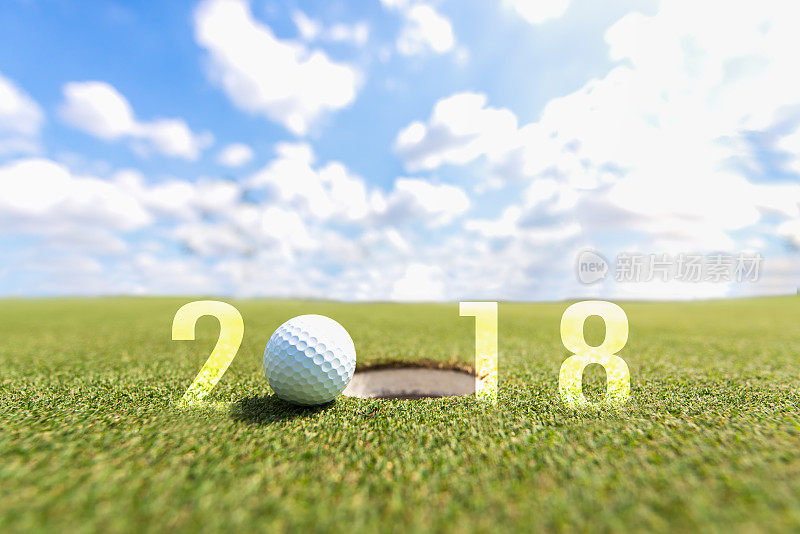 高尔夫运动概念形象。2018年新年快乐。高尔夫球在绿色的球道上，蓝天为背景。假日及运动概念