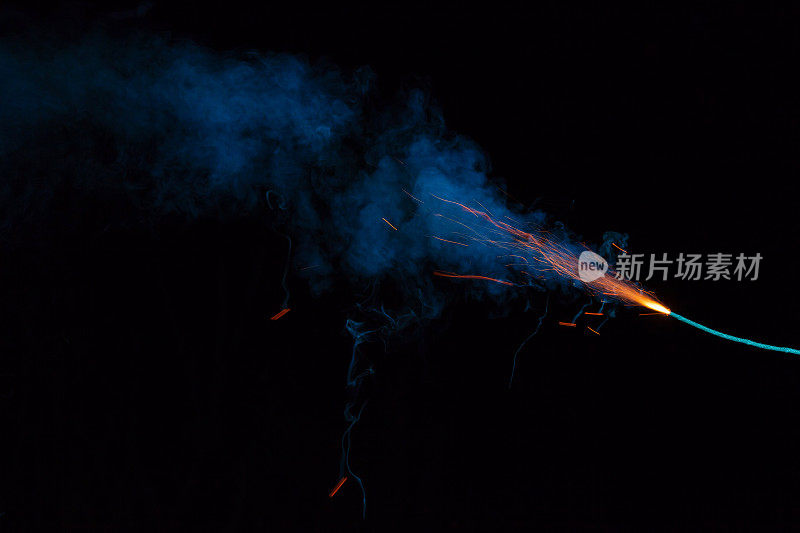 燃烧的引信与火花和蓝色烟雾在黑色的背景