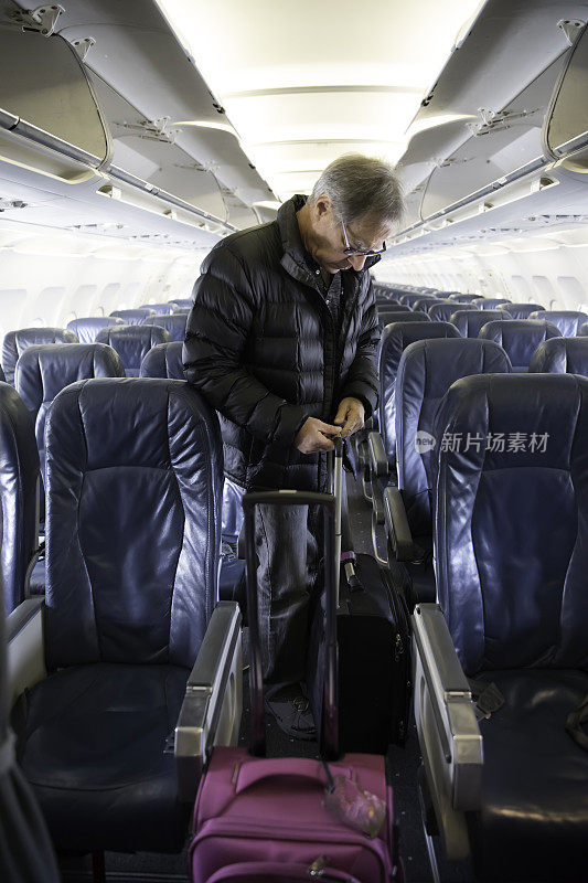 年长的白人男性在飞机上携带随身行李