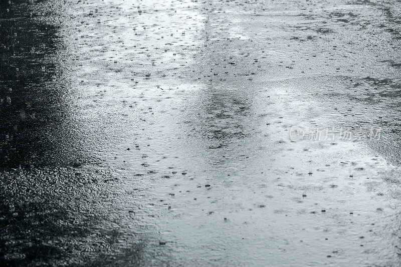 大雨时，潮湿的人行道上有水坑里的雨滴