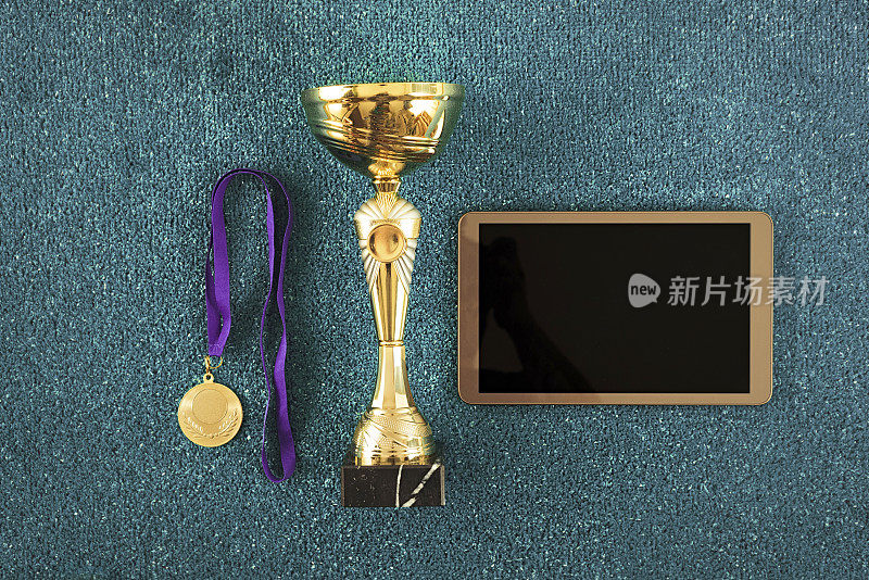 奖杯金杯和奖牌在蓝色红土球场与数字平板电脑