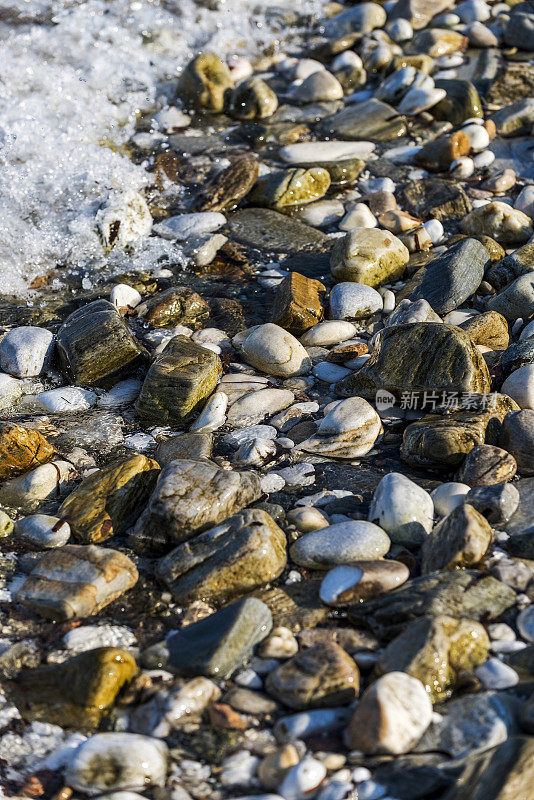 鹅卵石和波浪的背景在海滩，希腊