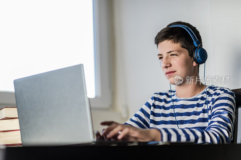 十几岁的男孩在家里休息的时候用笔记本电脑