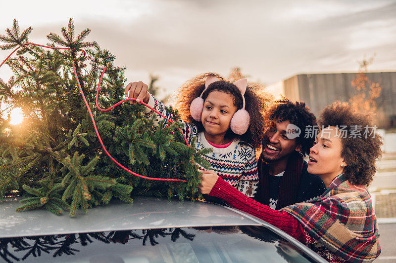 一家人把圣诞树挂在车顶上