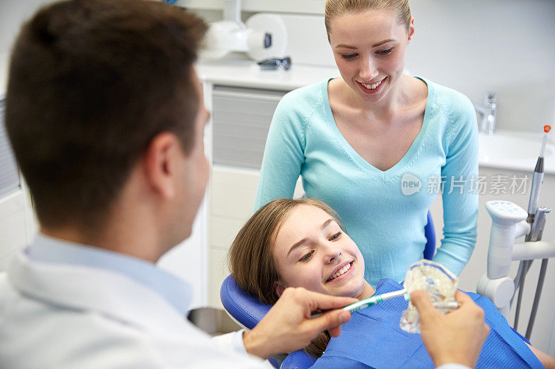 快乐的牙医向有耐心的女孩展示牙刷