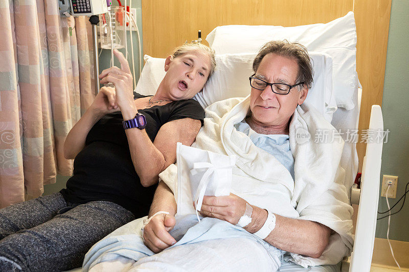 一位妇女和她生病的丈夫躺在医院的病床上