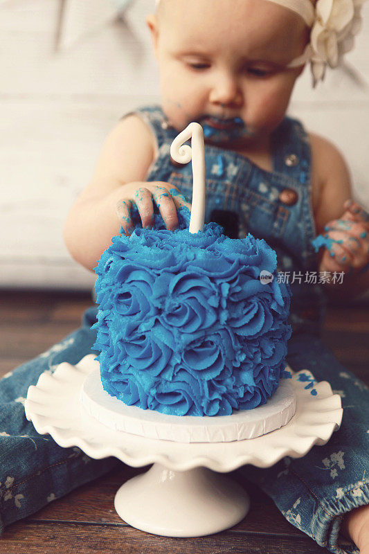 小女孩在吃她的第一个生日蛋糕