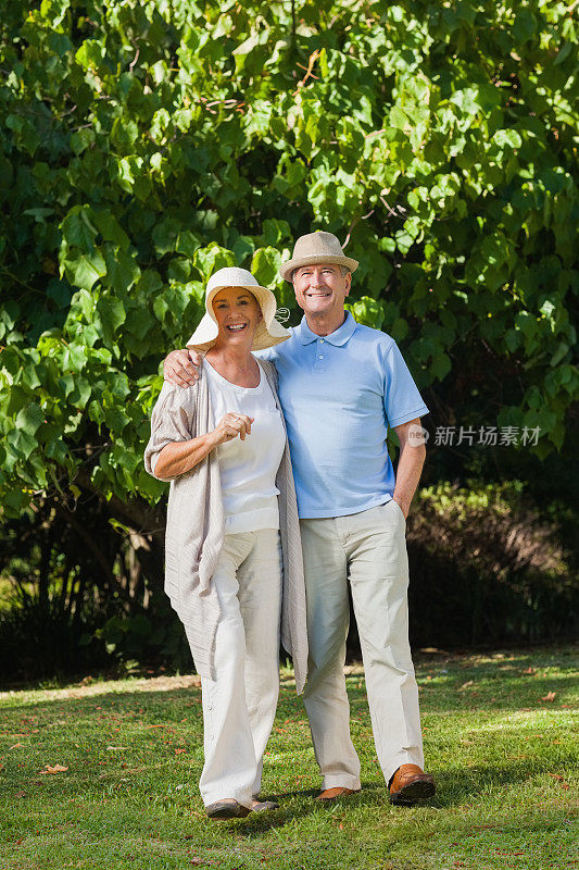 一对戴着草帽、面带微笑的老夫妇摆姿势