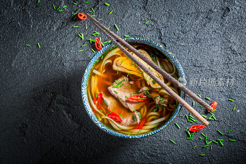 美味的红咖喱汤，用筷子夹在黑碗里