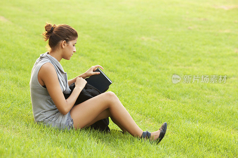 十几岁的女学生要在草地上学习。