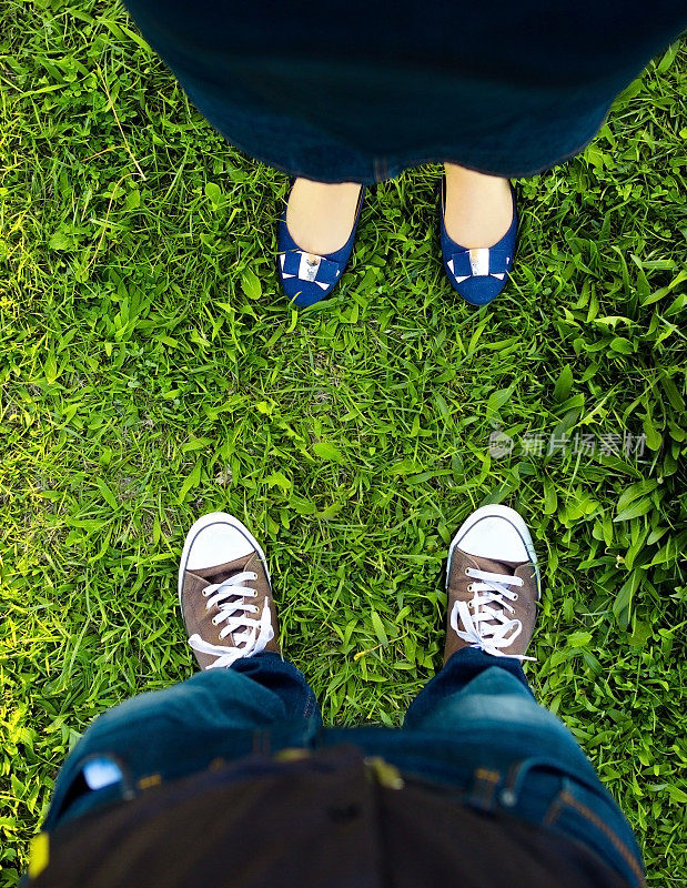 男式运动鞋和女式平底鞋在草地上对峙