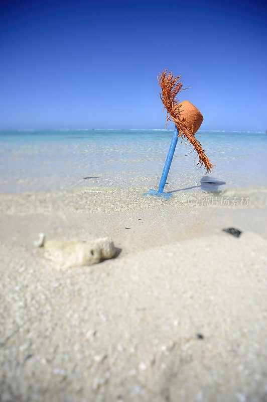 毛里求斯海滩上的蓝色玩具铲和橙色帽子