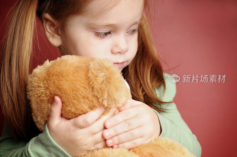 悲伤的小女孩抱着她的泰迪熊