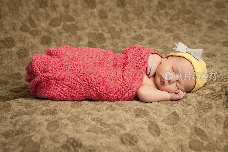 睡着的新生婴儿穿着黄色和红色的衣服