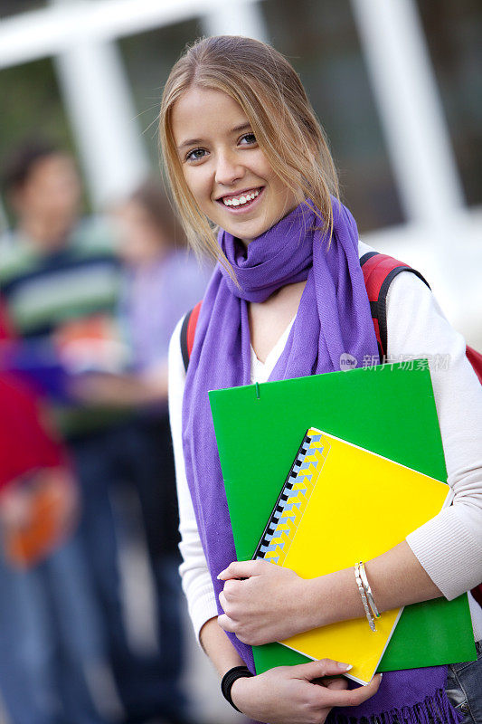 年轻的女学生站在学校前面