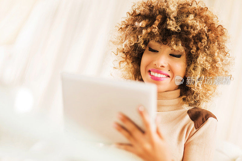 年轻微笑的非裔美国妇女使用触控板。
