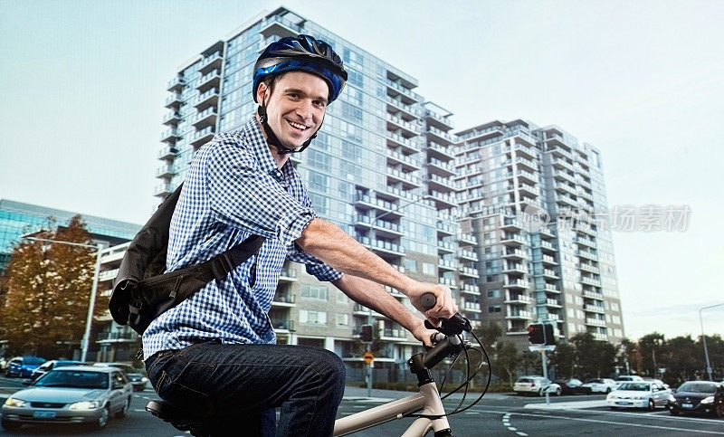 微笑的自行车手骑着自行车在城市前面