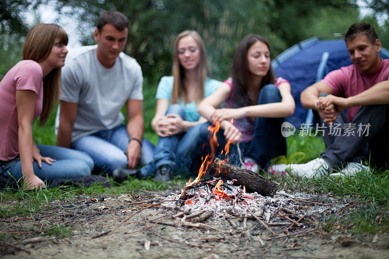 一群青少年坐在篝火旁。
