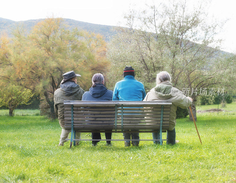 四个老人坐在公园的长椅上