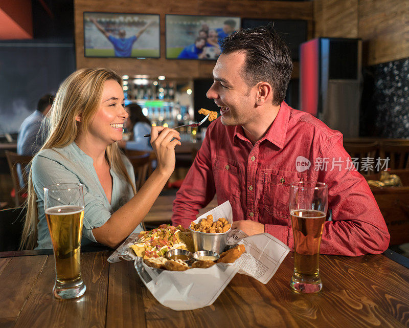 一对快乐的情侣在运动酒吧吃饭
