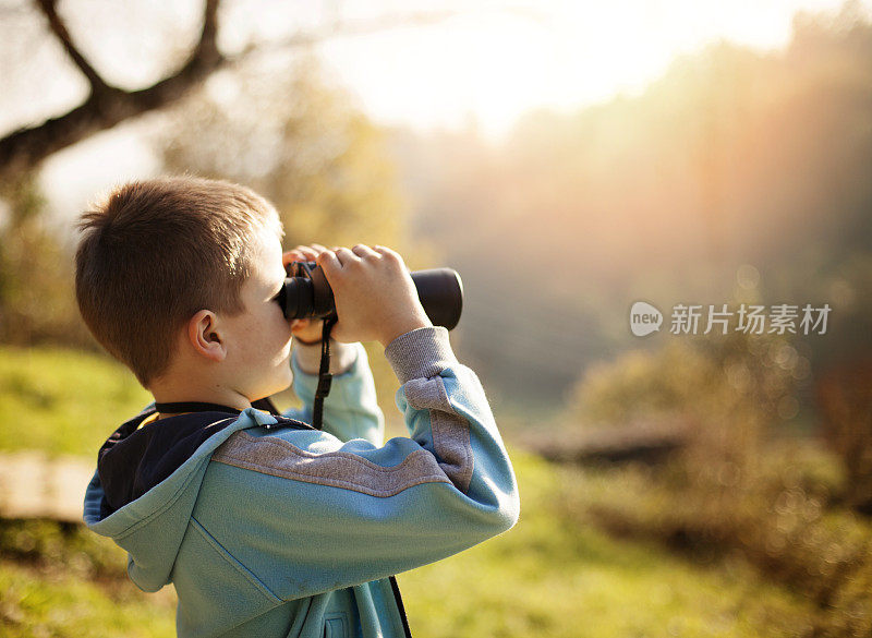 小男孩拿着望远镜在户外探险