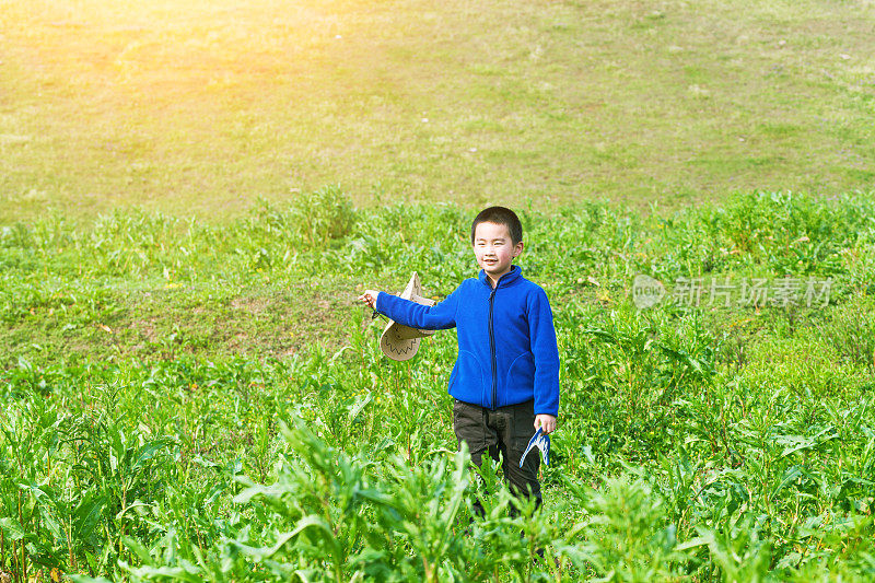 亚洲男孩带着纸飞机在草地上