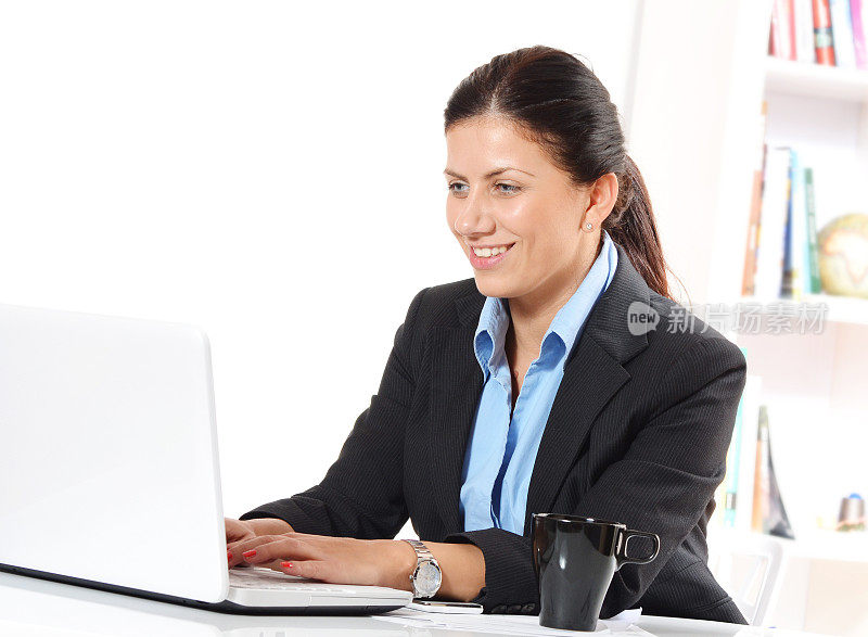 成功的商务女性在办公室用笔记本电脑打字和微笑