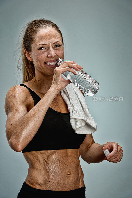 微笑的女运动员喝水