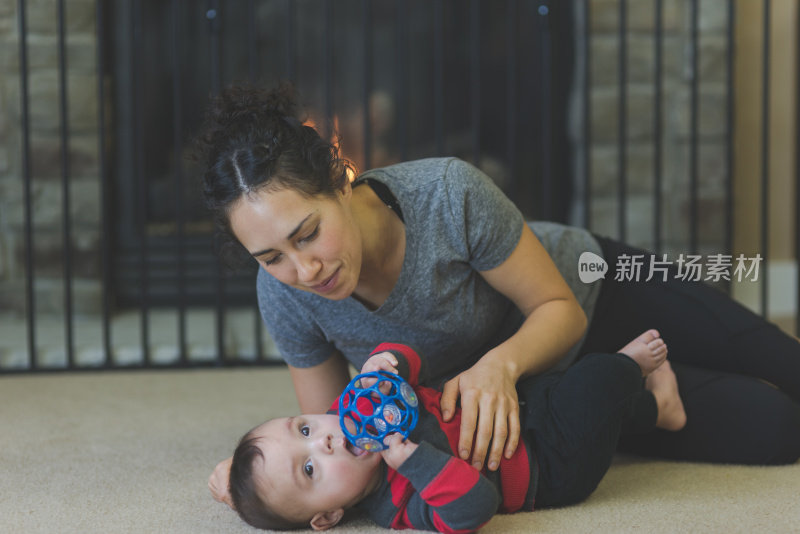 年轻的夏威夷妈妈和她六个月大的儿子在地板上玩耍