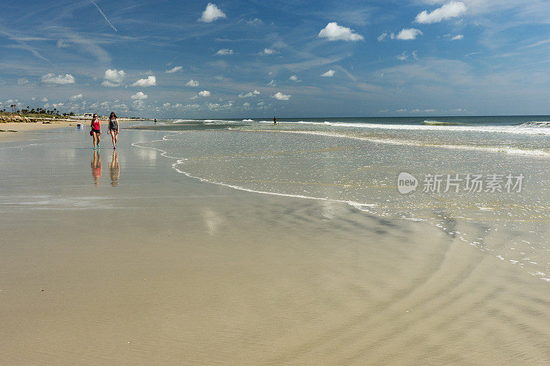 两个十几岁的女孩走在佛罗里达美丽的海滩上