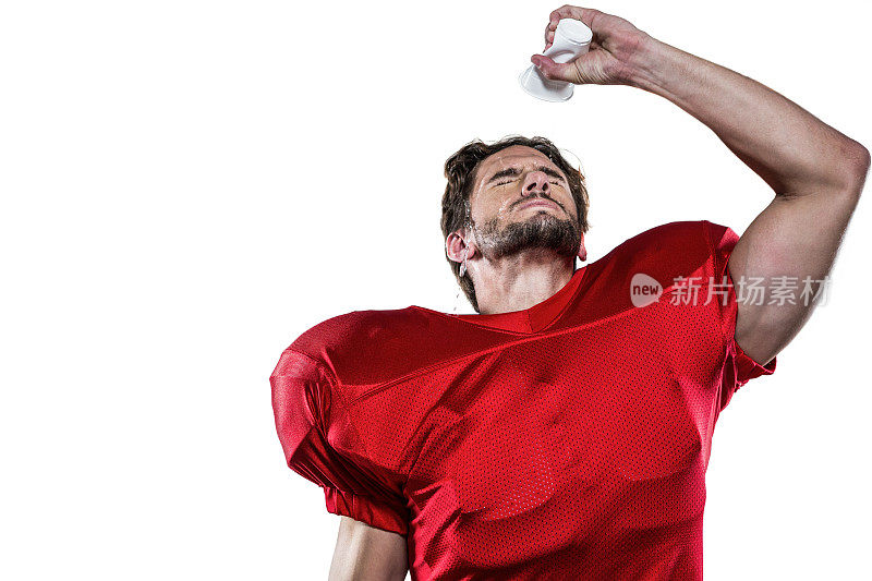 穿着红运动衫的美国足球运动员往脸上泼水