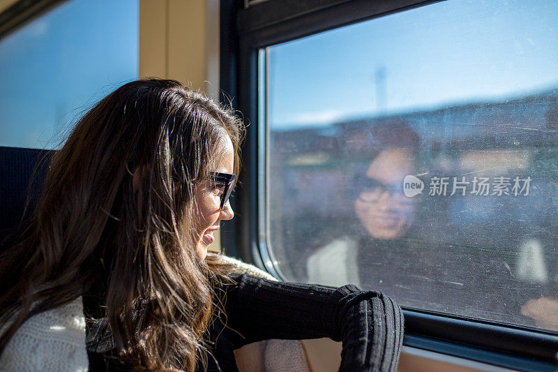 享受旅行。年轻漂亮的女人乘火车靠近窗户。火车的概念。