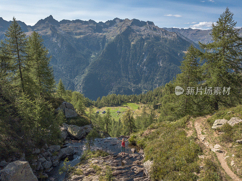 无人机鸟瞰图-夏天，年轻女子在河边徒步旅行，手臂张开庆祝个人进球