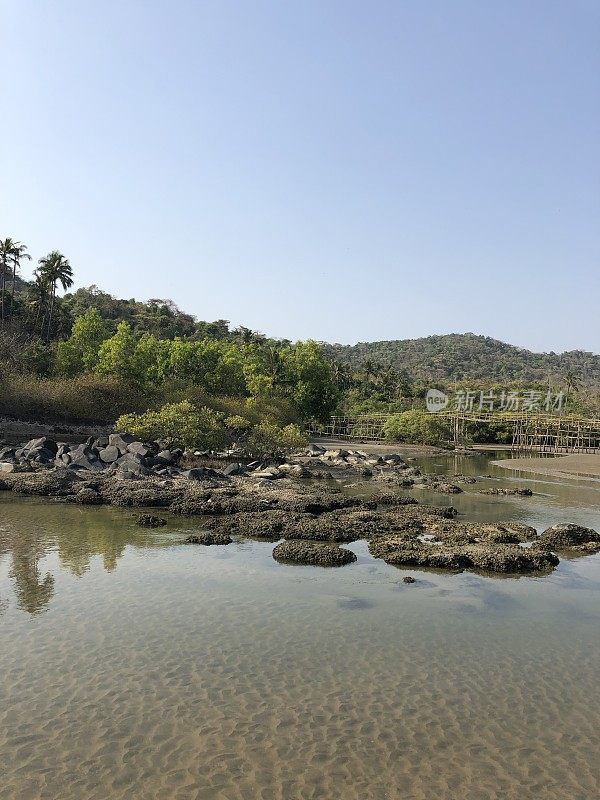 热带海滩岩石池泻湖椰子树，岩石，竹桥和金色的沙像天堂般的海滩度假照片，假日在果阿度假，Palolem海滩，南印度，海岸街道，天然岩石反射水面涟漪