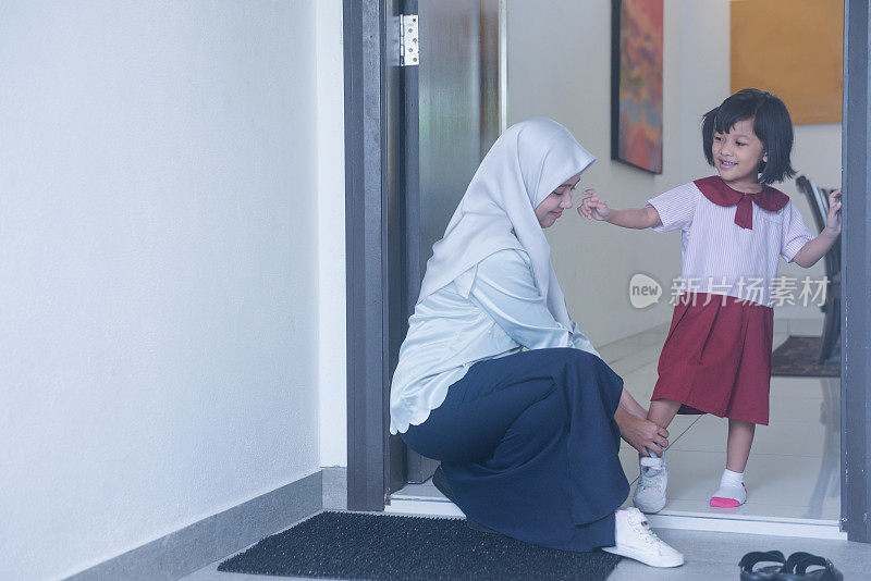 亚洲穆斯林年轻母亲让女儿准备离家上学