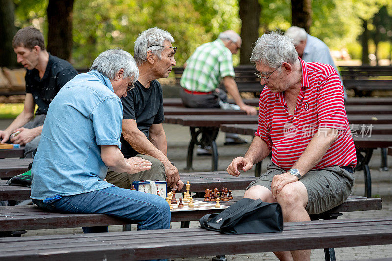 人们坐在公园的长椅上下棋。