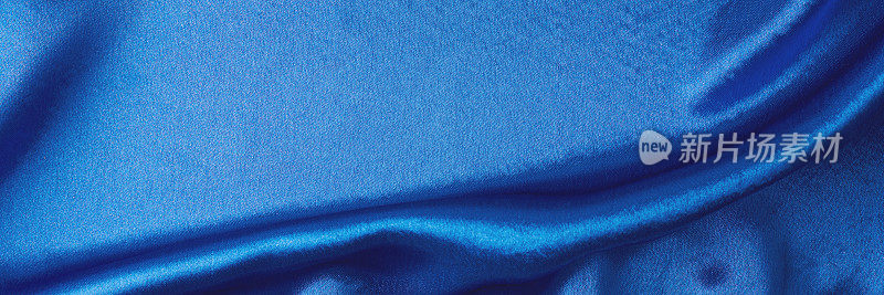 有褶皱的蓝色丝绸背景。抽象纹理的波纹缎面，长横幅