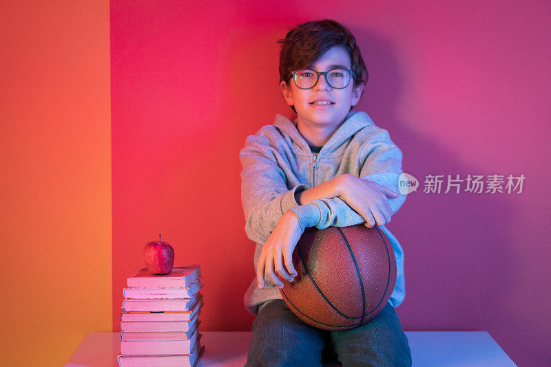 一个男生拿着篮球坐在桌子上