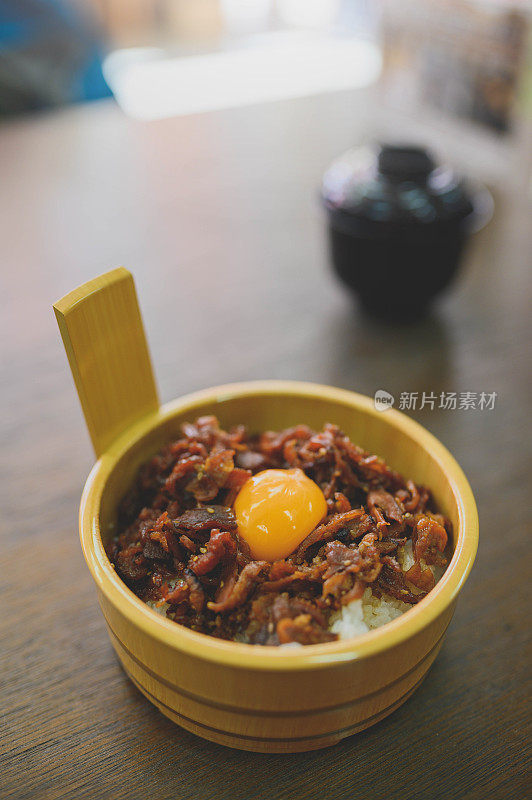 日式料理-将牛肉片放在盛有温泉蛋的碗上