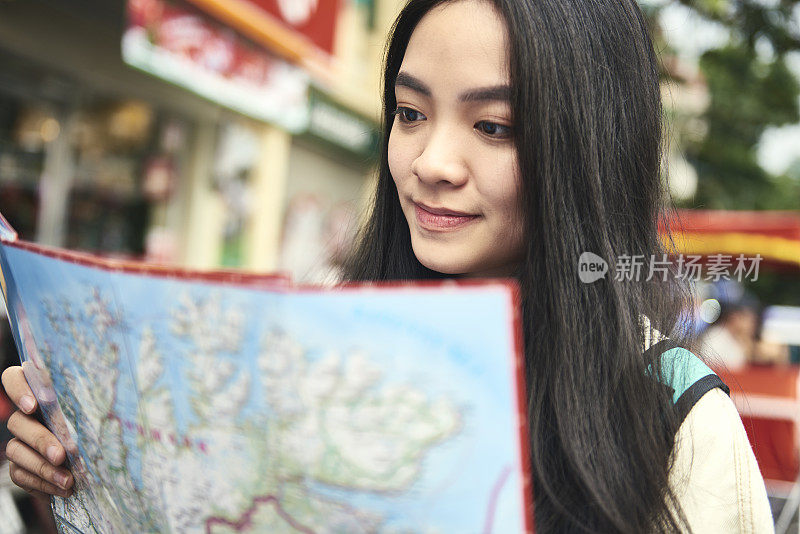 亚洲妇女在街上使用纸质地图