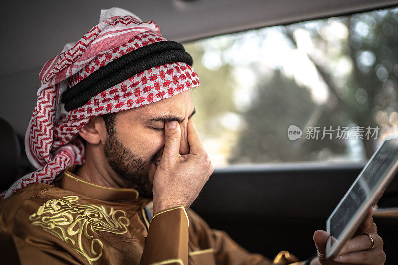 忧心忡忡的中东阿拉伯人在汽车上使用数字平板电脑